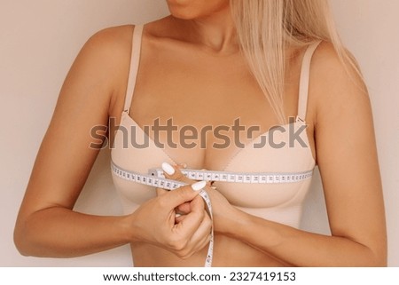 Cropped shot of young slim blonde woman measuring her measures the chest circumference with a centimeter isolated on beige background. Diet, sport healthy lifestyle, wellness concept. Model parameters Royalty-Free Stock Photo #2327419153