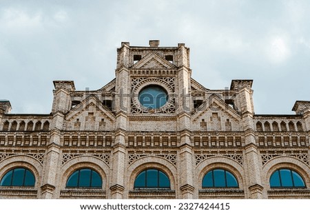 Facade of an old brick building with a tower. Building against the sky. Old building with a clock. Beautiful old architecture. University park. Tourist place of Kyiv. Gothic architecture. Royalty-Free Stock Photo #2327424415