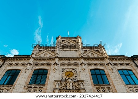 Facade of an old brick building. Building against the sky. Old building with a clock. Beautiful old architecture. Gothic architecture. Royalty-Free Stock Photo #2327424417