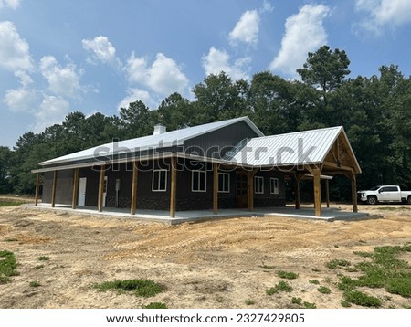 Post frame pole barn construction with metal siding and metal roofing, concrete flooring, heavy beams, bardominimum Royalty-Free Stock Photo #2327429805
