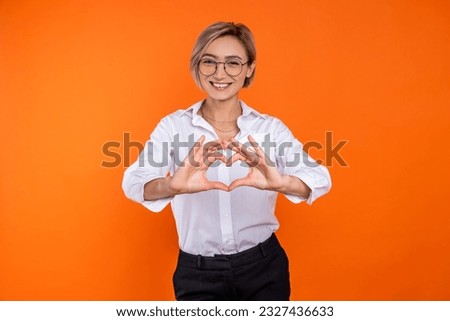 Romantic woman wearing white official style shirt showing heart shape with hands Royalty-Free Stock Photo #2327436633