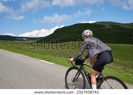Female cyclist riding a road bike with a view of the mountains.Training for competition.Practicing cycling on open country road. Bucegi Natural Park.