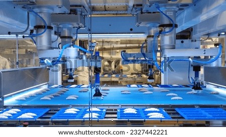 Modern factory for the production of French croissants around the world. High-tech robots put French croissants into containers. Long moving production line with delicious french croissants. Royalty-Free Stock Photo #2327442221