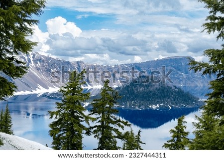 View through the pine trees into the deep blue waters of the Caldera of Crater Lake in Oregon.