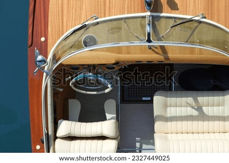 Helm boat. The front of a wooden boat on a blue background top view. Expensive wooden lacquered part of the boat. Fore deck. Wooden deck on a blue background top view. Boat with white leather chair Royalty-Free Stock Photo #2327449025