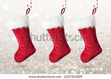 Three red Christmas stockings hanging from candy canes on sparkly glittery background
