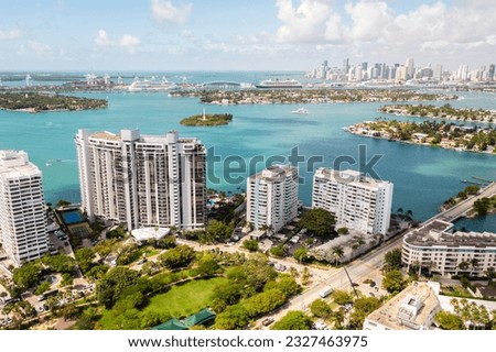 Aerial drone Shot in Miami, USA, commercial area, luxury houses, buildings and mansions, abundant tropical vegetation around, blue sky and Ocean.
