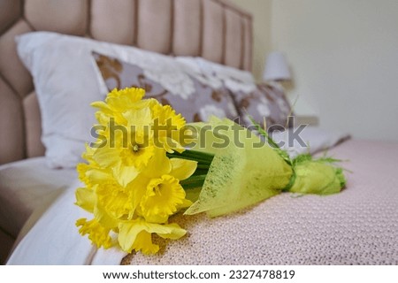 Bouquet of yellow flowers on bed in bedroom