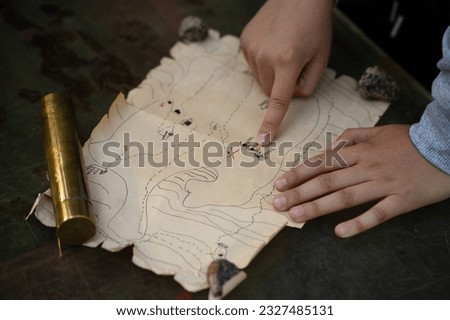 The child's finger points to the buried treasure on the map.A game of pirates in the fresh air.Treasure hunting with a child in nature. Pirate Map