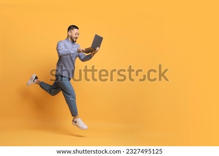 Online Sales. Excited Young Asian Man With Laptop Computer Running Over Yellow Background, Happy Millennial Male Looking At Screen And Smiling, Enjoying Website Offer, Full Length, Copy Space Royalty-Free Stock Photo #2327495125