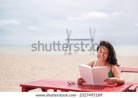 attractive latin girl reading a book on the beach