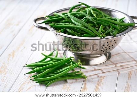 green beans in a steel strainer sieve metal on a white wooden table, selective focus. Royalty-Free Stock Photo #2327501459