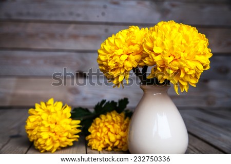 Flowers. Beautiful yellow chrysanthemum in vintage pottery vase. Old wooden background