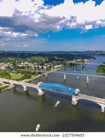 aerial shot of a gorgeous summer landscape along the Tennessee River with the Walnut Street Bridge and the Chief John Ross Bridge with lush green trees, blue sky and clouds in Chattanooga Tennessee Royalty-Free Stock Photo #2327504603