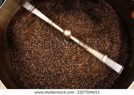 fresh coffee beans roasted spinning cover professional machine close up to soft focus  slow shutter speed because want to make motion blur of coffee beans detail concept, at factory chiang rai 