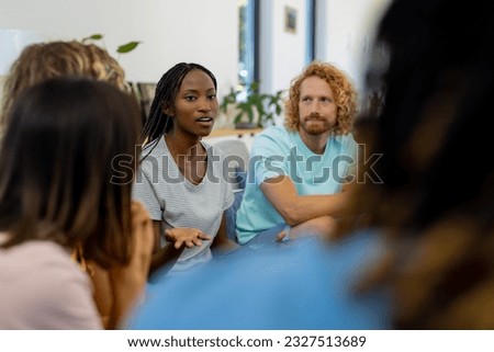 Group of diverse people sitting on sofa and talking in group therapy session. Lifestyle, friendship and support, togetherness, unaltered. Royalty-Free Stock Photo #2327513689