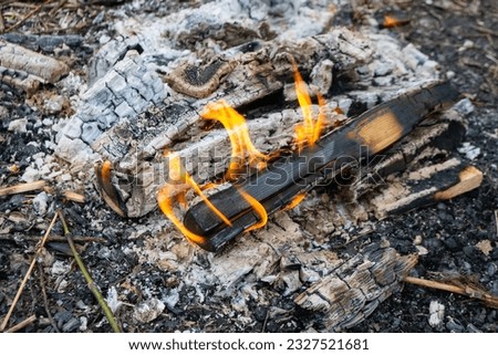 A fire burns in a campfire with a red fire in the background. High quality photo