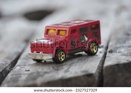 Toy car in red color on a wooden background
