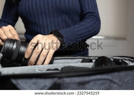 Young woman putting away her camera lens. Traveling photographer concept.