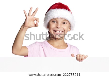 Happy little Santa Claus. Smiling Christmas little boy in red Santa hat peeking from blank board, isolated on white background. Space for text.