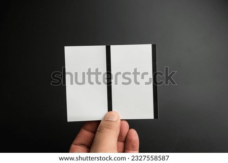 Male hand holding two blank sheets of paper tickets on a black background