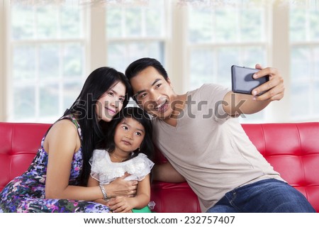 Cheerful family looking and smiling at camera phone when take a self portrait