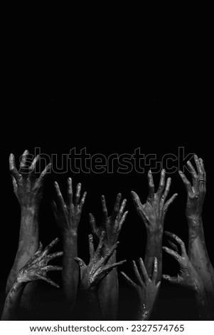 Halloween night background of numerous scary and creepy zombie hands rising from dark shadows, creating a spooky atmosphere ideal for horror themed celebrations and events Royalty-Free Stock Photo #2327574765