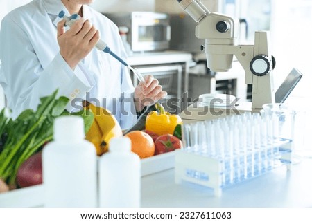 A young researcher observing the ingredients of vegetables under a microscope. Registered dietitian. Royalty-Free Stock Photo #2327611063