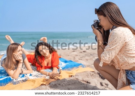 Woman photographer taking pictures of her friends on the beach, with an old-fashioned camera