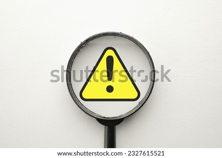 Magnify glass focus on Exclamation mark on a yellow sing or Warning sign over white background Attention sign,Exclamation mark,warning sign concept. Royalty-Free Stock Photo #2327615521