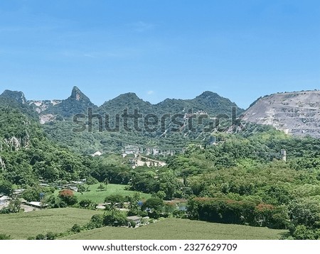 A limestone quarry surrounded by mountains and trees.