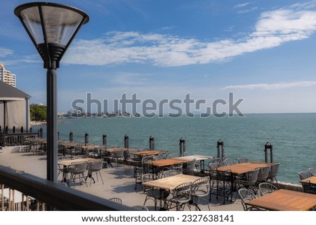 Summer terrace with stylish trendy outdoor furniture at a luxurious travel destination. Wooden desk of free space and summer background of beach.