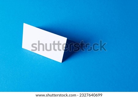 White business card with copy space on blue background. Business, business card, stationery and writing space concept.