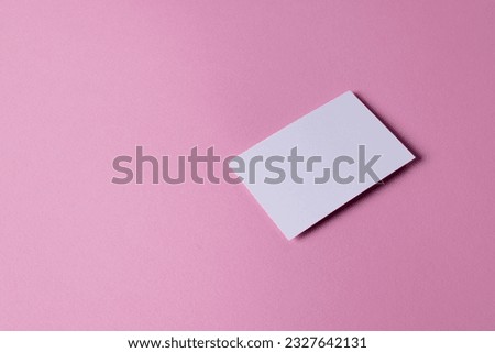 White business card with copy space on pink background. Business, business card, stationery and writing space concept.