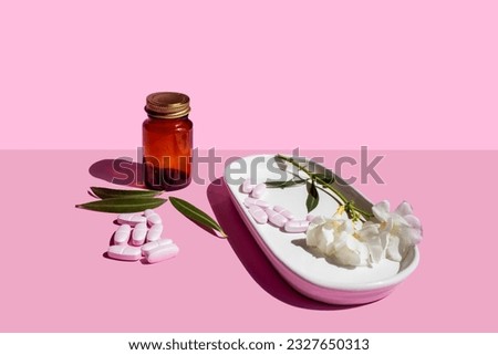 collagen pills, medicine jar and flowers on pink background Royalty-Free Stock Photo #2327650313