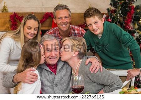 Multigeneration family with little girl kissing her grandfather at home in the living room