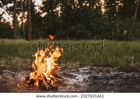 A Lonely Evening by the Forest Campfire - Embracing the Beauty of Nature with the Fire Burning at Dusk near a River, Against the Enchanting Evening Sky Royalty-Free Stock Photo #2327651661