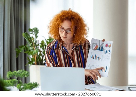 A red-haired businesswoman confidently presents data and analytics in a video call. With expertise and visuals, she embodies professionalism, capturing impactful virtual presentations in this image