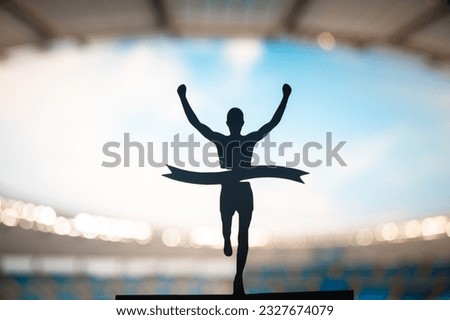 Crossing Boundaries: Runner's Silhouette Breaks the Finish Line Tape at Modern Athletics Stadium. Edit Space, Track and Field Competition Photo.
