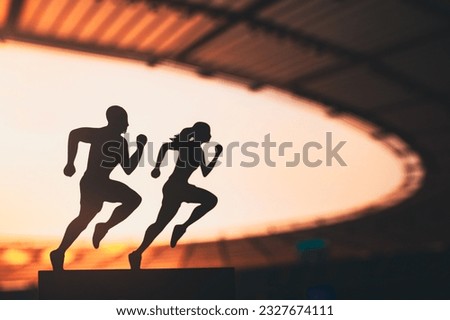 Synchronized Strides: Silhouettes of Male and Female Runners in Tandem, Gracefully Racing against a Modern Sports Stadium Backdrop