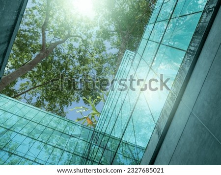 Eco-friendly building in the modern city. Sustainable glass office building with trees for reducing heat and carbon dioxide. Office building with green environment. Corporate building reduce CO2.  Royalty-Free Stock Photo #2327685021