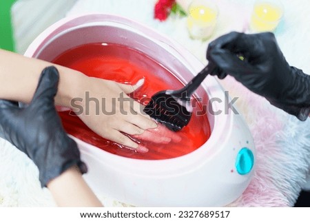 Beautiful Asian young woman having a paraffin foots and hands spa at beauty - spa shop. Foot and hand paraffin treatment. Royalty-Free Stock Photo #2327689517