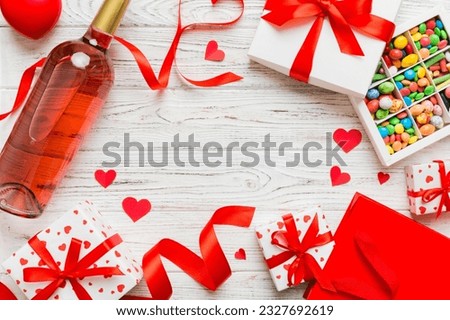 top view photo of st valentine day decor shopping, bag, wine, bottle, envelope, gift, box, candy and red heart on colored background with empty space. Frame background.
