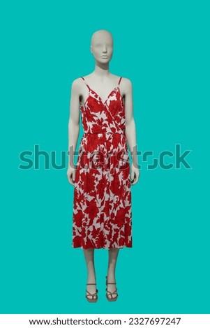 Full length image of a female display mannequin wearing red-white fashionable dress with floral pattern isolated on blue background