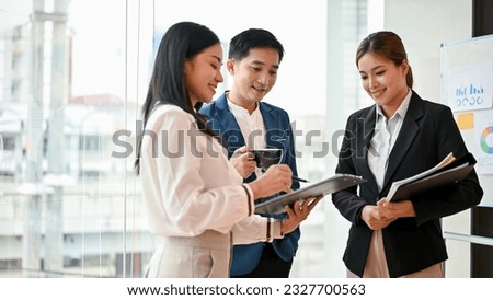 A professional and smart millennial Asian male boss is talking with his female employees, giving advice on a project, and discussing work in the office. Royalty-Free Stock Photo #2327700563