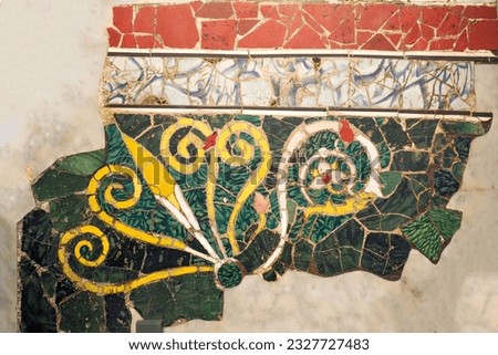 Ancient wall adorned with a vibrant handmade freeform-tiles mosaic, showcasing a floral pattern. Royalty-Free Stock Photo #2327727483