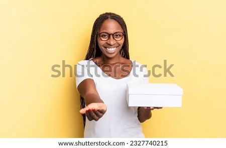 smiling happily with friendly, confident, positive look, offering and showing an object or concept and holding an empty box
