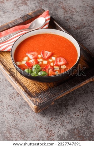 Spanish tomato soup gazpacho with strawberries, cucumbers and basil close-up in a bowl on the table. Vertical
 Royalty-Free Stock Photo #2327747391