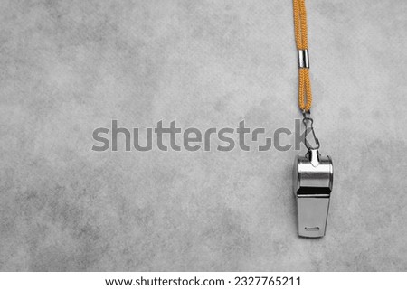 One metal whistle with cord on light grey table, top view. Space for text Royalty-Free Stock Photo #2327765211
