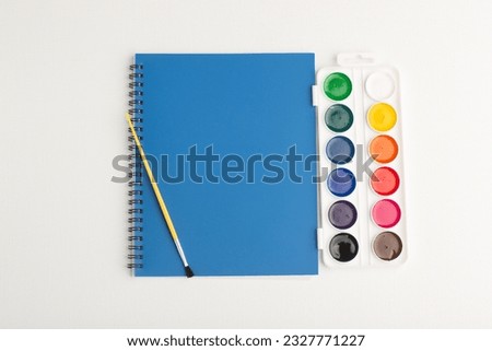 top view blue copybook with colorful paints on white background drawing art paint color